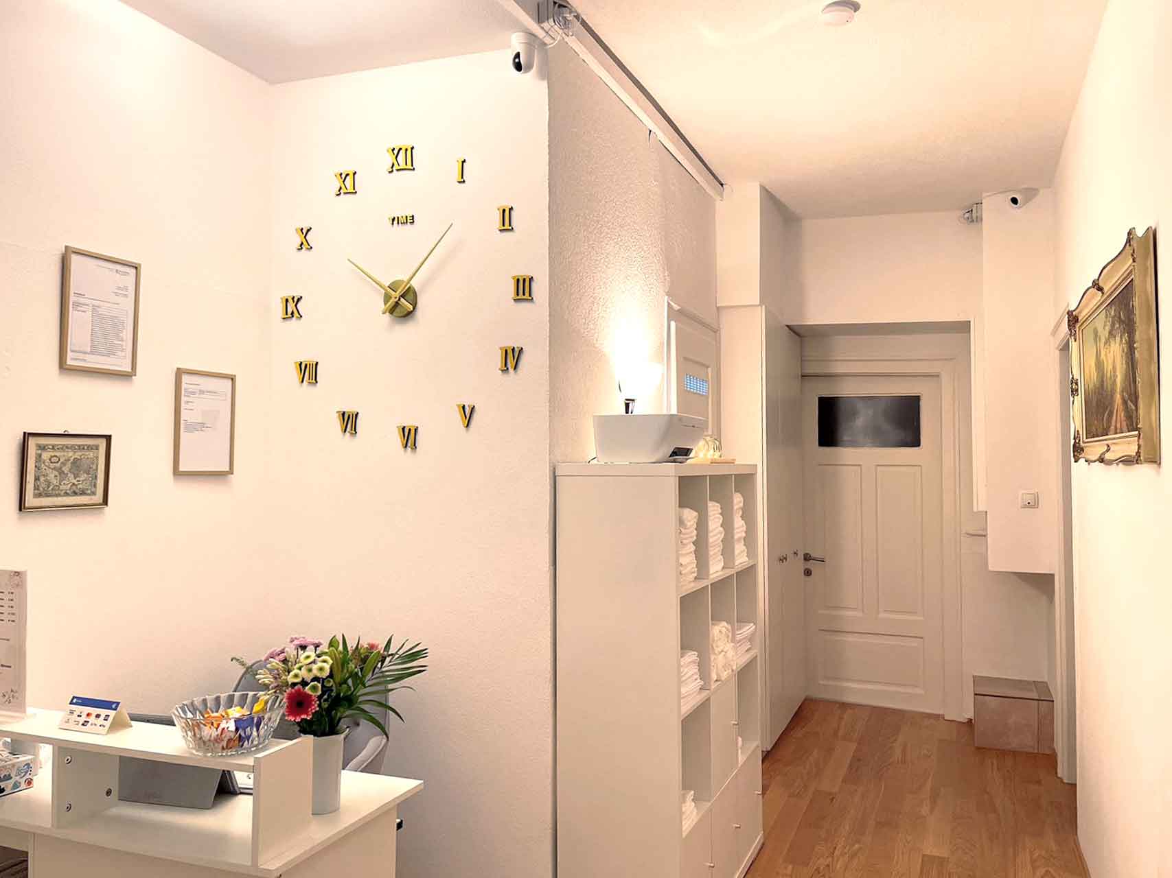 Eingangsebreich mit einer Uhr, Bilder und Urkunden an der Wand und einem Schrank mit Handtuecher